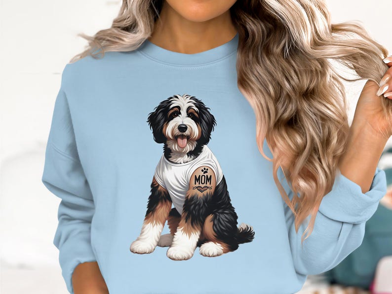 A woman wearing a light blue sweatshirt with a graphic of a dog on it.