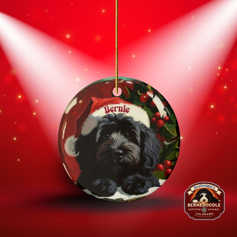 A black bernedoodle dog wearing a santa hat that is personalized with their name on it in this adorable Ceramic ornament!  Design appears on the front and the back of this doodle dog ornament!