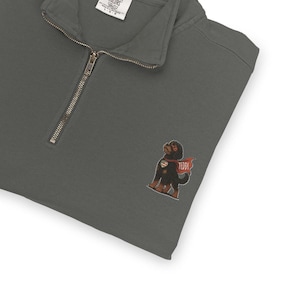 Pu&ograve; includere: Felpa grigio scuro con zip a un quarto e una piccola grafica ricamata di un cane nero con un mantello rosso con il nome "TEDDI". La felpa ha una vestibilit&agrave; rilassata e una sensazione morbida e confortevole.