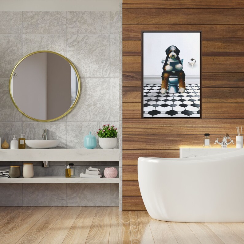 May include: A framed wall art print featuring a black, white, and brown dog sitting on a white toilet while reading a book. The dog is positioned in a bathroom with a black and white hexagonal tiled floor and a white wall background.