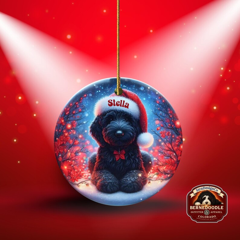 Capture the magic of the season with this adorable black Goldendoodle puppy wearing a festive Santa hat, surrounded by glowing red berries and twinkling snowflakes! Perfect personalized Christmas tree ornament for doodle parents. Add your dog's name (like "Stella") for a heartfelt touch. High-quality ceramic, vibrant print, gold string included. Ideal dog mom/dad gift, stocking stuffer, or memorial keepsake. Handmade holiday charm!