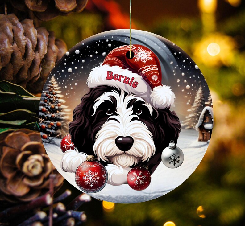 Personalize your holiday decor with this charming Bernedoodle Christmas ornament! Featuring a cute Bernedoodle in a festive Santa hat and customizable name, this round ornament adds warmth and joy to any tree. Perfect for dog lovers and unique gifts!