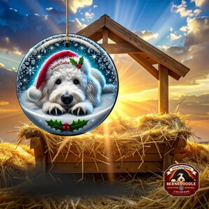 May include: A round Christmas ornament featuring a white dog wearing a Santa hat with the word "Snowflake". The ornament has a winter scene with snowflakes and holly. A gold string is attached for hanging.