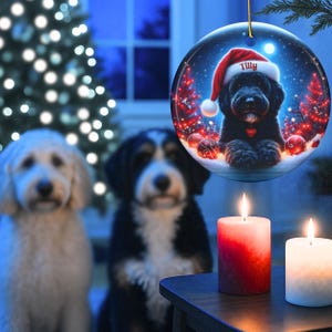 This festive ornament features an adorable black doodle wearing a Santa hat, surrounded by soft glowing holiday lights and rich red Christmas tones. The warm lighting highlights the dog’s fluffy black fur, giving the design a bright, cheerful look that stands out on any tree. A perfect personalized keepsake for anyone who loves black doodles and joyful holiday décor.