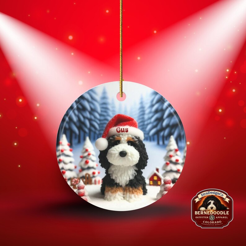 Bernedoodle claymation style ornament made of ceramic, hanging by a gold string.  Winter scene featuring a cute, personalized doodle dog with personalized name on santa hat.  Perfect gift for Bernedoodle Dog Lovers and Pet Enthusiasts.