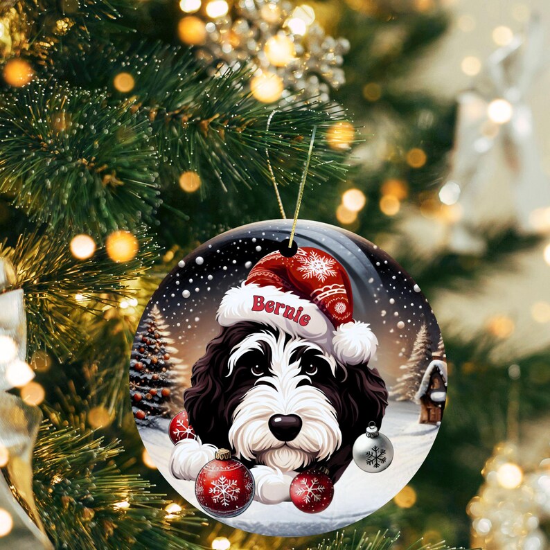 Personalize your holiday decor with this charming Bernedoodle Christmas ornament! Featuring a cute Bernedoodle in a festive Santa hat and customizable name, this round ornament adds warmth and joy to any tree. Perfect for dog lovers and unique gifts!