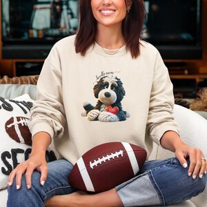 A woman wearing a Bernedoodle sweatshirt with cute design on the front and the back.  The front features a bernedoodle dog in claymation design holding a heart with his name, across the top of his head the words, "Doodle Mom".