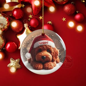 This ceramic ornament features a cute red mini-doodle golden doodle or goldendoodle dog wearing a Santa hat in a snow globe setting, surrounded by holiday decorations. Perfect for adding a festive touch to your Christmas tree or as a thoughtful gift for dog lovers.
