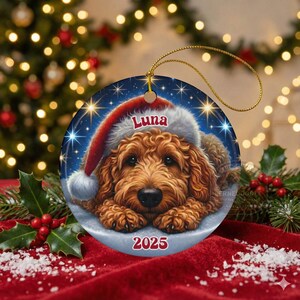 A ceramic ornament of a goldendoodle dog wearing a Santa hat, personalized with the dog's name and the year.  Gorgeously placed in a warm background with candles and Christmas lights.