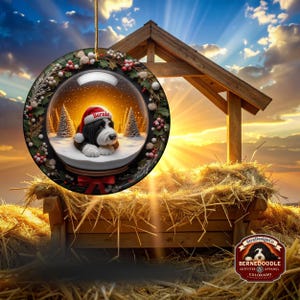 May include: A round Christmas ornament featuring a Bernedoodle dog inside a snow globe, wearing a Santa hat. The ornament is decorated with holly and berries. The word "Bernie" is on the hat.