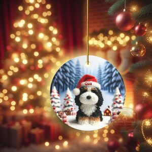 Bernedoodle claymation style ornament made of ceramic, hanging by a gold string.  Winter scene featuring a cute, personalized doodle dog with personalized name on santa hat.  Perfect gift for Bernedoodle Dog Lovers and Pet Enthusiasts.