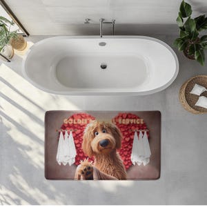 A cute golden doodle stands in front of a fluffy red heart backdrop, holding a brown towel on a cozy bath mat. White towels hang on either side, creating a spa-like feel. The text “Goldie’s Towel Service” sits above the doodle. Perfect for dog lovers, bathroom décor, and pet-themed home accents.
