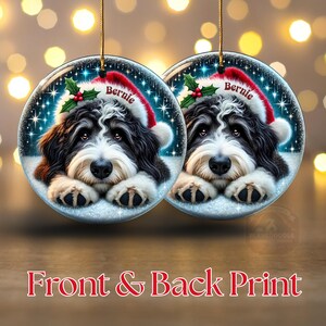 May include: Two round Christmas ornaments featuring a Bernedoodle dog wearing a Santa hat with the name "Bernie". The ornaments have a snowy background with twinkling lights and holly. The text "Front & Back Print" is at the bottom.