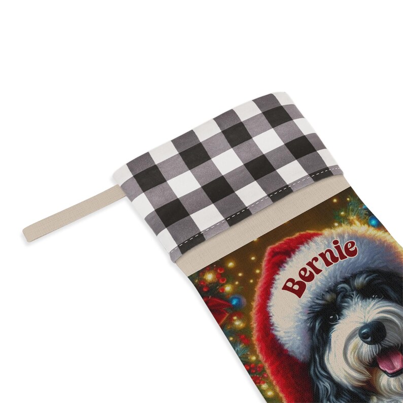 May include: Christmas stocking with a black and white dog wearing a Santa hat, with the name "Bernie". The stocking has a black and white checked cuff and a beige hanging loop.