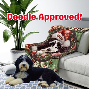 May include: A cozy throw blanket featuring a black and white dog wearing a Santa hat, with the name "Bowie" on it. The blanket has a festive design with Christmas elements. The words "Doodle Approved!" are displayed in red text.