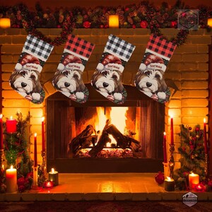 A festive Christmas stocking featuring a whimsical illustrated doodle dog wearing a red Santa hat, surrounded by holiday ornaments and greenery in a warm, detailed Christmas art style. The top of the stocking has a classic red and black buffalo-plaid cuff, and the stocking hangs from a white mantel decorated with evergreen garland and gold ornaments. The stocking design is personalized with your dog’s name, making it a charming and custom holiday décor piece for dog lovers.