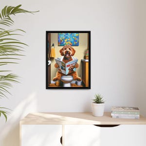 Puede incluir: Una impresi&oacute;n enmarcada muestra un perro marr&oacute;n sentado en un inodoro, leyendo una "Dog Magazine". La escena est&aacute; ambientada en un ba&ntilde;o, con una pintura y una toalla amarilla. La impresi&oacute;n est&aacute; en un marco negro.