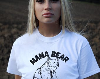 May include: White t-shirt with a black and white illustration of a bear and the text "Mama Bear".