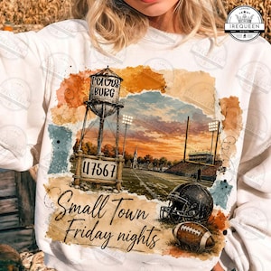 May include: A white sweatshirt featuring a graphic print of a water tower labeled Petersburg 47567, a football field with goalposts, a helmet, and a football. The text Small Town Friday nights is printed in black script below the illustration.