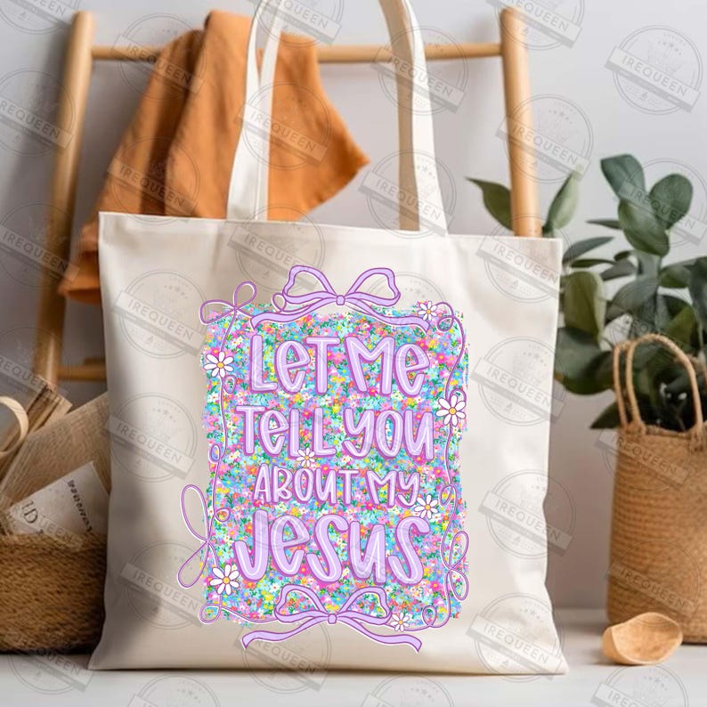 May include: Cream-colored tote bag with the text "Let Me Tell You About My Jesus" in a colorful floral design. The bag has a rectangular design with a bow and daisy accents.