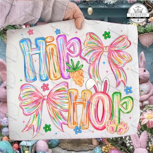 May include: A white graphic featuring the words "Hip Hop" in colorful bubble letters, with bows, flowers, a carrot, and bunny ears. The design has a rainbow color scheme with glitter accents, perfect for Easter.