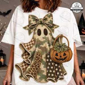 May include: A white t-shirt featuring a large ghost graphic with a camouflage pattern, a bow on top, and a pumpkin basket. The ghost design incorporates various textures including leopard print, polka dots, and checkered patterns in shades of green and brown.