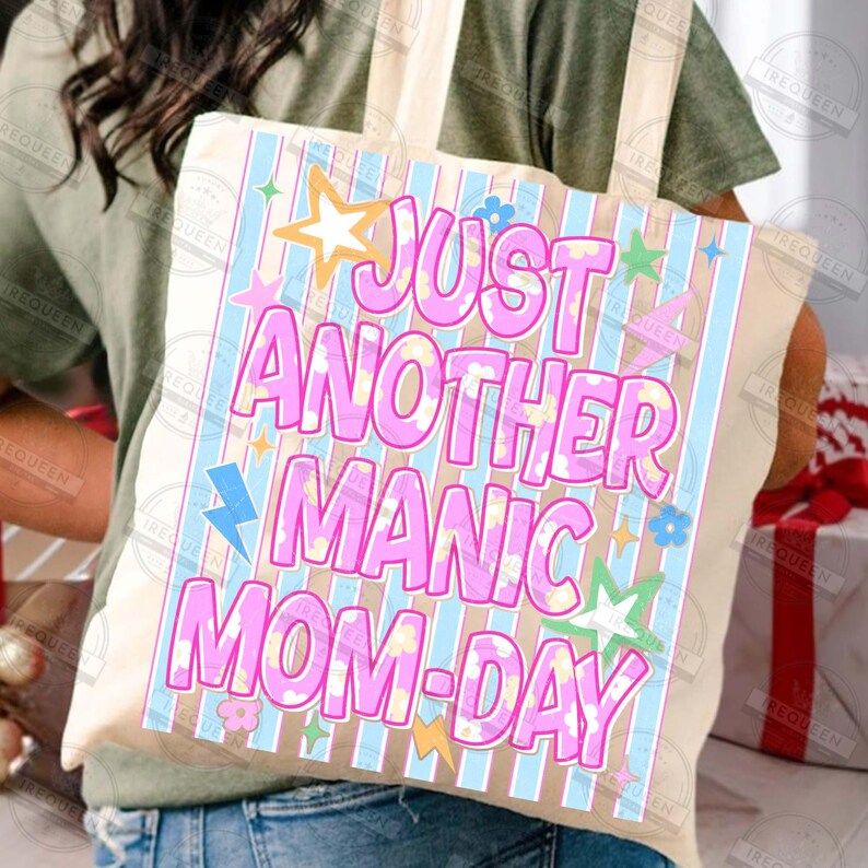 May include: Beige tote bag with the text "JUST ANOTHER MANIC MOM-DAY" in pink, decorated with stars, flowers, and lightning bolts. The bag has blue and beige vertical stripes.