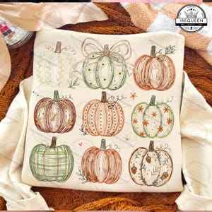 Puede incluir: Una sudadera de color crema con un estampado gráfico de nueve calabazas estilizadas dispuestas en cuadrícula. Las calabazas están ilustradas con varios patrones de líneas, incluyendo rayas, cuadros y motivos florales, en tonos naranja, verde y marrón.