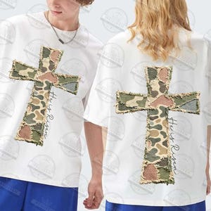 May include: White t-shirts with a large, camouflage-patterned cross design on the front and back. The text "He is Risen" is printed vertically on the right side of the cross. The cross has a distressed, frayed edge.