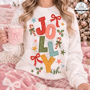 Può includere: Una felpa bianca a maniche lunghe con la parola JOLLY in grandi lettere testurizzate multicolori. Il design include fiocchi rossi, bastoncini di zucchero, foglie di agrifoglio verdi e piccole stelle di vari colori. La parola ish è stampata in verde.