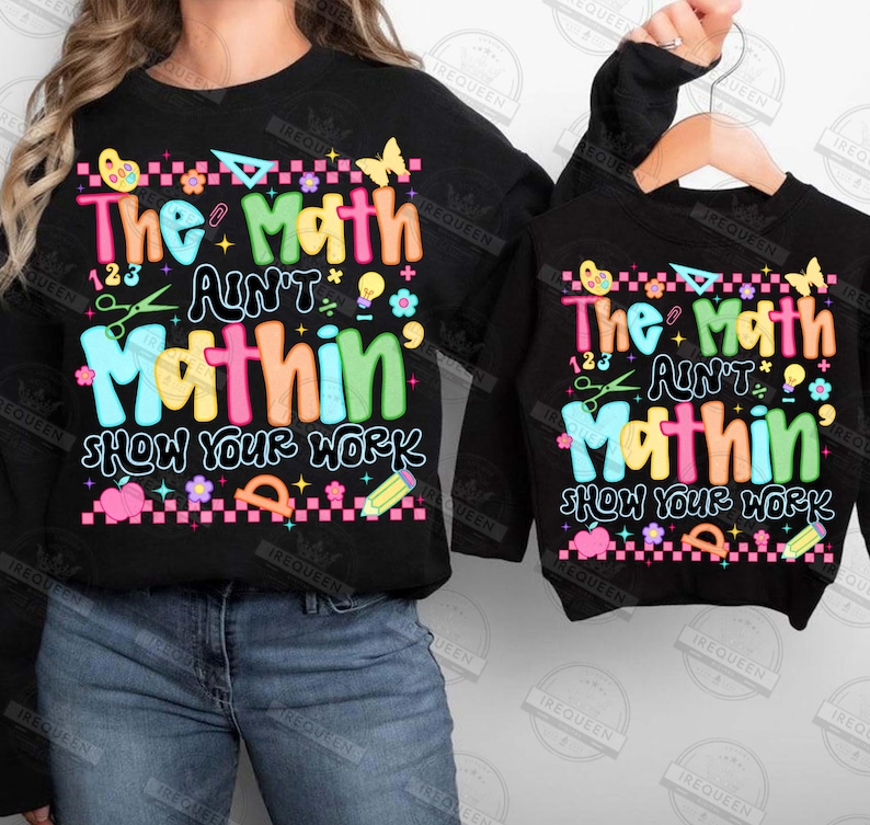 Puede incluir: Sudaderas negras con el texto "The Math Ain't Mathin' Show Your Work" en letras coloridas y gr&aacute;ficos. El dise&ntilde;o incluye mariposas, tijeras y un l&aacute;piz. Una sudadera es para adultos, la otra para ni&ntilde;os.