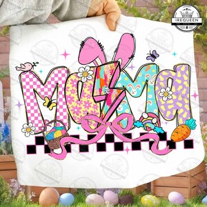 May include: A white graphic featuring the word "MAMA" in colorful, patterned letters with Easter-themed illustrations. The design includes bunny ears, a basket of eggs, flowers, a butterfly, a rainbow, and a carrot. A pink bow and a black and white checkered border complete the design.