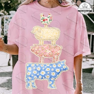 May include: Pink t-shirt featuring a stacked farm animal design. The design includes a chicken, sheep, pig, and cow, each with a unique floral pattern and outlined with a pearl-like trim. The cow is blue with white daisies.