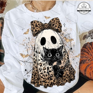 May include: White sweatshirt featuring a Halloween-themed graphic. The design includes a ghost wearing a leopard print bow and holding a black cat. Spiderwebs, bats, and stars complete the spooky design.