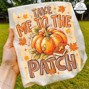 May include: A white t-shirt featuring a graphic print with the text TAKE ME TO THE PATCH in brown letters. The design includes a large orange pumpkin with green leaves, a brown book with a gold cross on the cover, and scattered orange maple leaves.