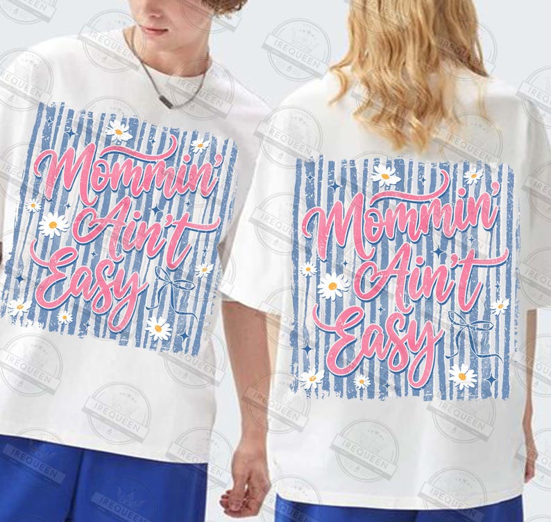 May include: White t-shirts with the text "Mommin' Ain't Easy" in pink script, set against a blue striped background, adorned with daisy accents. The shirts are short-sleeved and have a casual fit.