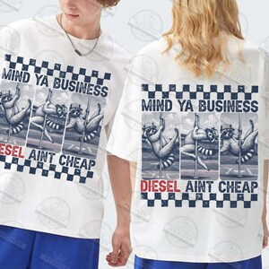 May include: White t-shirts with a graphic design featuring raccoons pole dancing. The text "MIND YA BUSINESS" is above the graphic, and "DIESEL AINT CHEAP" is below. The design has a checkered border.