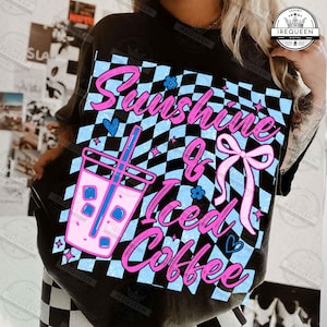 May include: Black t-shirt with a checkerboard pattern in black and light blue. The shirt features a graphic of a pink iced coffee drink and the words "Sunshine & Iced Coffee" in pink script.