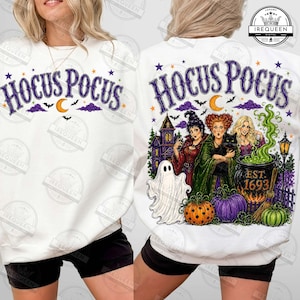 May include: A white sweatshirt featuring a Hocus Pocus graphic. The front displays the text Hocus Pocus with stars, bats, and a crescent moon. The back shows the three Sanderson sisters, a ghost, a black cat, a cauldron labeled Est. 1693, and pumpkins.