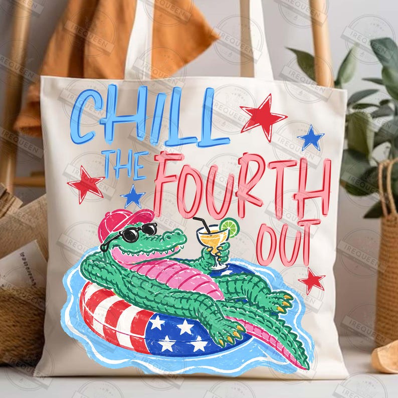 May include: Cream tote bag with a vibrant graphic of an alligator wearing sunglasses and a red hat, floating on a patriotic ring with a cocktail. Text reads "CHILL THE FOURTH OUT" in blue and pink, with star accents.