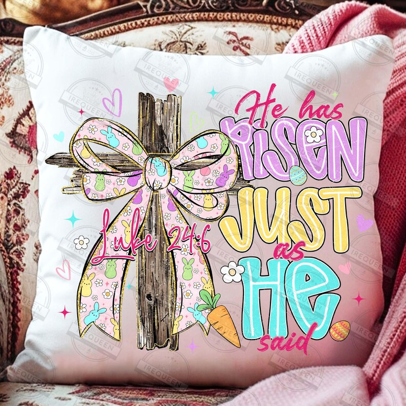 May include: White square pillow with a colorful Easter design. The design includes a wooden cross with a pink bow adorned with bunnies and flowers. Text reads "He has risen just as He said" and "Luke 24:6".