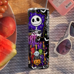 May include: A cylindrical stainless steel tumbler featuring a vibrant purple and black graphic print of characters from The Nightmare Before Christmas, including Jack Skellington, a pumpkin, and various spooky motifs with white bats and spiderwebs.