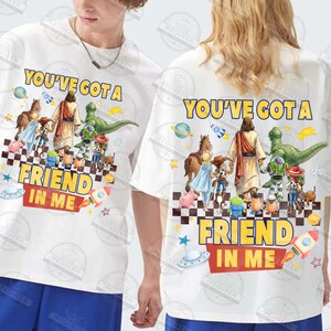 May include: White t-shirts with a colorful graphic featuring the text "YOU'VE GOT A FRIEND IN ME" and cartoon characters. The design includes a rocket, a spaceship, and a checkerboard pattern.