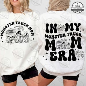 May include: White sweatshirt with black text that reads "Monster Truck Mom" on the front and "In My Monster Truck Mom Era" on the back. The sweatshirt features a black and white illustration of a monster truck on the front.