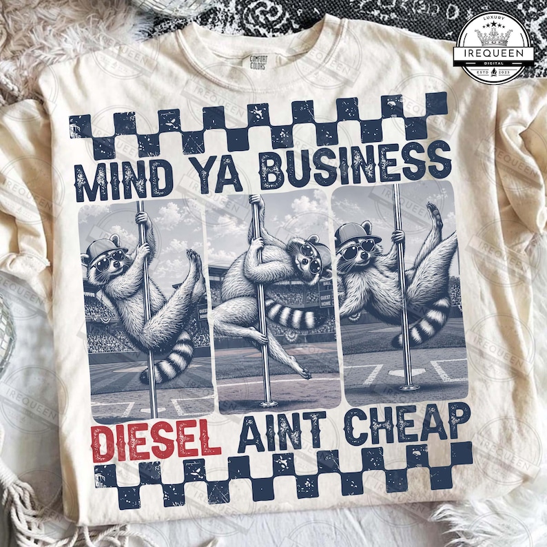 May include: Cream-colored sweatshirt with a graphic featuring three raccoons pole dancing. The text "MIND YA BUSINESS" is above the raccoons, and "DIESEL AINT CHEAP" is below. The design includes a checkered pattern.