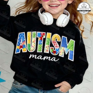 以下が含まれることがあります： カラフルなパッチワーク文字で「AUTISM」、白い筆記体で「mama」と書かれた黒いスウェットシャツ。文字は水玉模様、花柄、パズルピースなど、さまざまなパターンで埋められています。スウェットシャツは人が着ています。