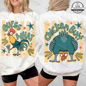May include: A white sweatshirt featuring a graphic print of a rooster with the text "GUESS WHAT" on the front and a chicken with the text "Chicken Butt" on the back. The design includes yellow vertical stripes, teal stars, and orange accents.