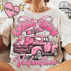 Puede incluir: Camiseta blanca con un gráfico rosa. Presenta una camioneta rosa vintage llena de globos en forma de corazón. El texto dice "SMALL TOWN Valentine" y "HOMETOWN". También hay un corazón rosa con "CUSTOM TEXT".