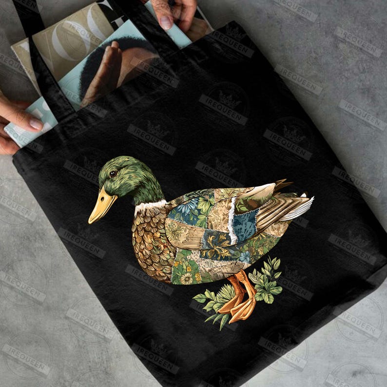 May include: Black tote bag featuring a detailed illustration of a duck with a patchwork design on its body. The duck has a green head, yellow beak, and orange feet. The bag is made of a durable material and has black handles.