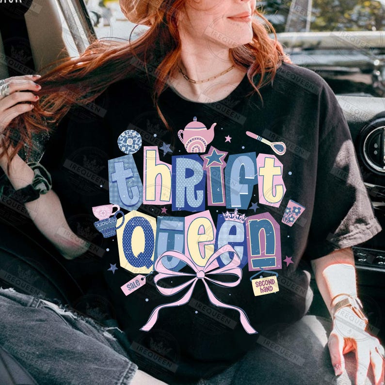May include: Black t-shirt with the words "Thrift Queen" in a colorful, layered design. The design includes a pink bow, stars, and illustrations of a teapot, teacup, and spoon. The words "sale" and "second hand" are also included.